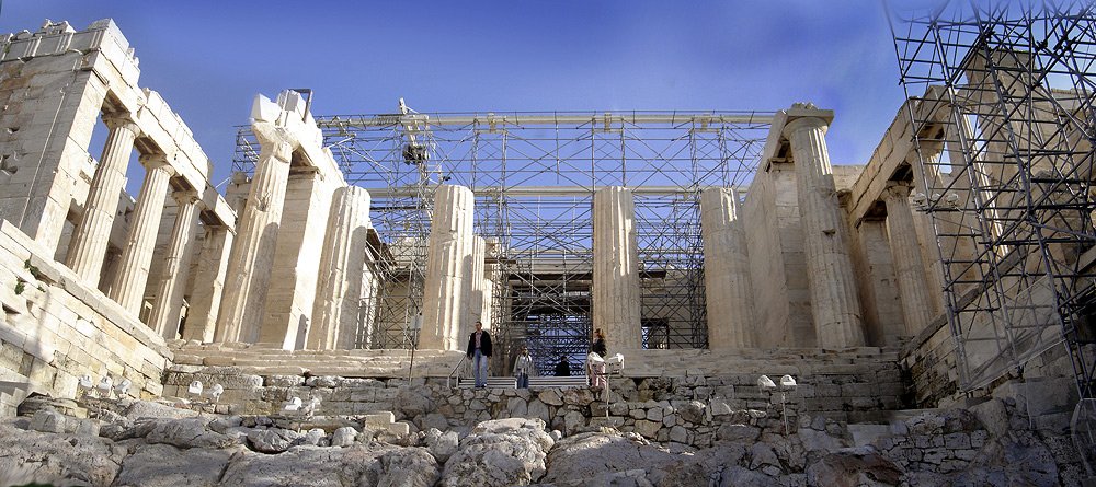 The Propylaea, the ceremonial entrance gate to the Acropolis, photographed from the path below with its Doric columns and central staircase rising toward the summit.