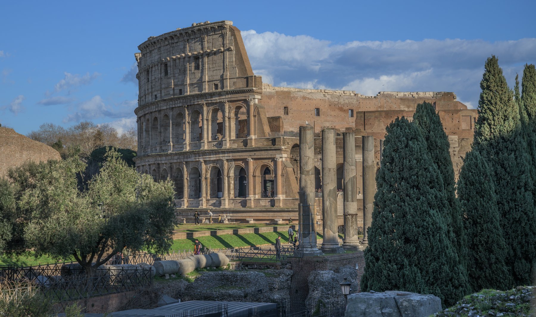 The Colosseum in Rome seen from the south with the Roman Forum in the foreground, the outer travertine arcades catching late afternoon light.
