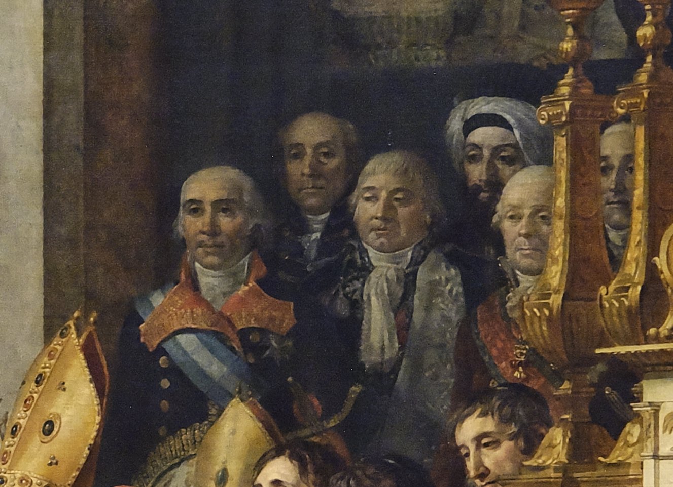 Detail of a group of dignitaries in dark coats and sashes, one with a pale blue sash and red collar, and behind them a bearded man in a white turban, partly screened by gilded candlesticks.