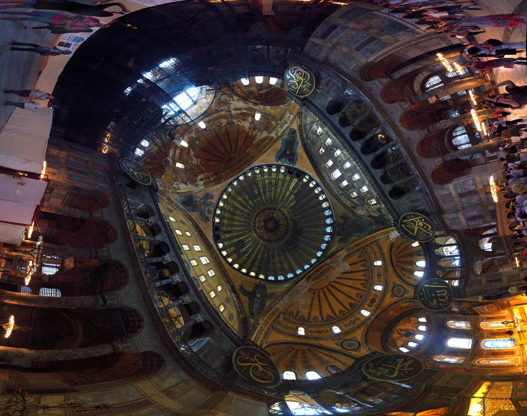 A panoramic view of the interior of Hagia Sophia showing the nave, the secondary half-domes, the gallery level, and the central dome rising above marble revetment walls.