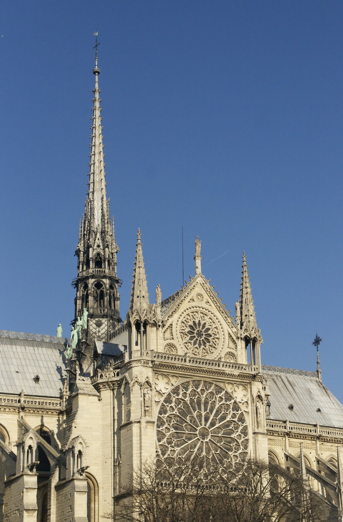 Inside Notre-Dame de Paris, looking up at the south rose window in the transept, a wheel of stained glass in deep red and blue panels around a central figure.