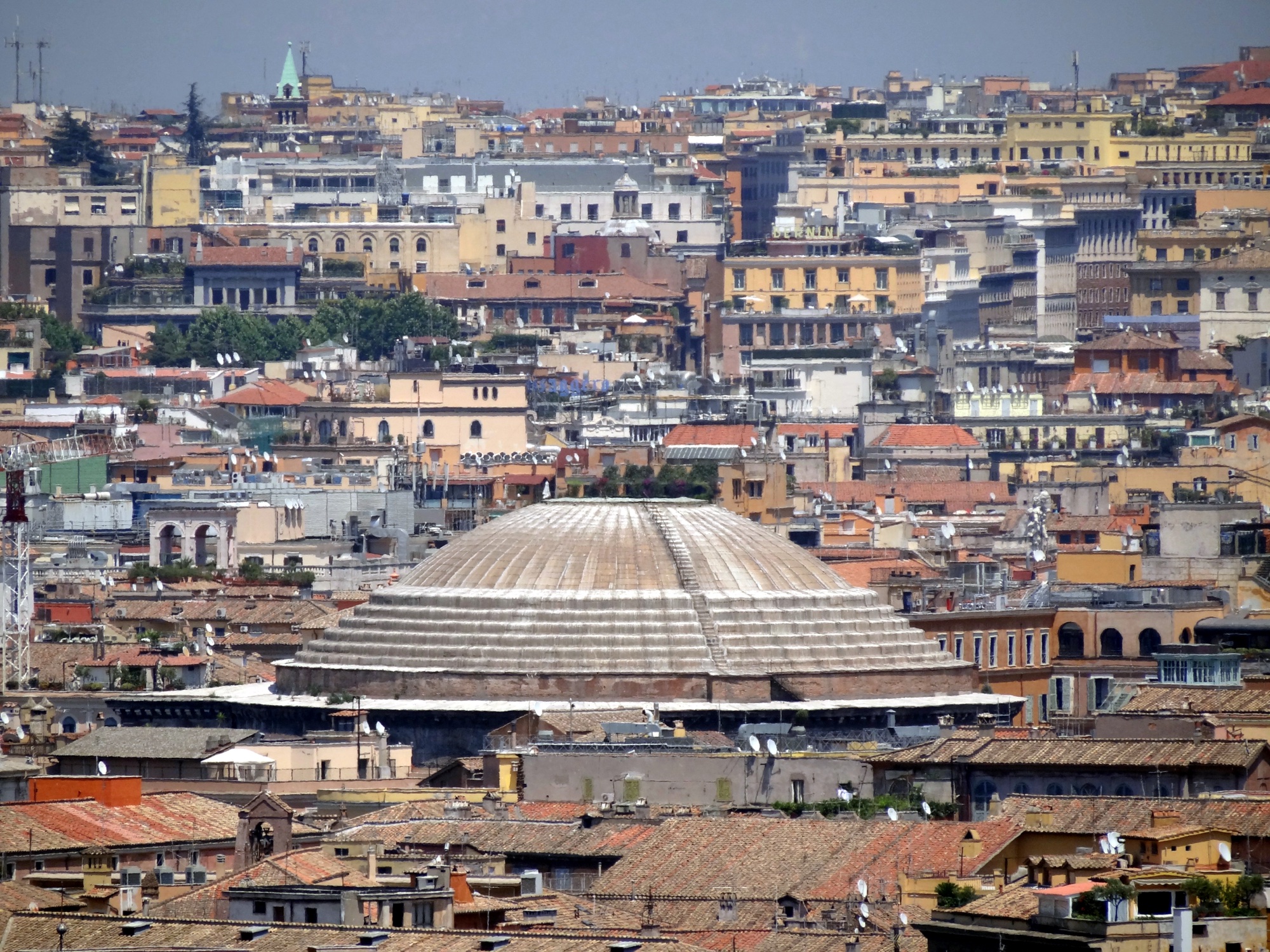 The Pantheon seen across the rooftops from the Gianicolo hill: the shallow curve of the dome rising above Rome with no structural buttressing visible anywhere on its exterior.