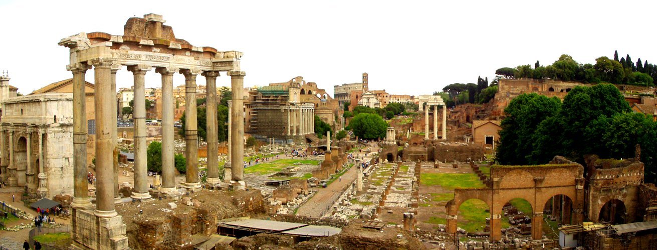 Panoramic view of the Roman Forum from the Capitoline Hill, showing the columns of the Temple of Saturn in the foreground, the Arch of Septimius Severus on the left, and the ruins stretching east toward the Colosseum.
