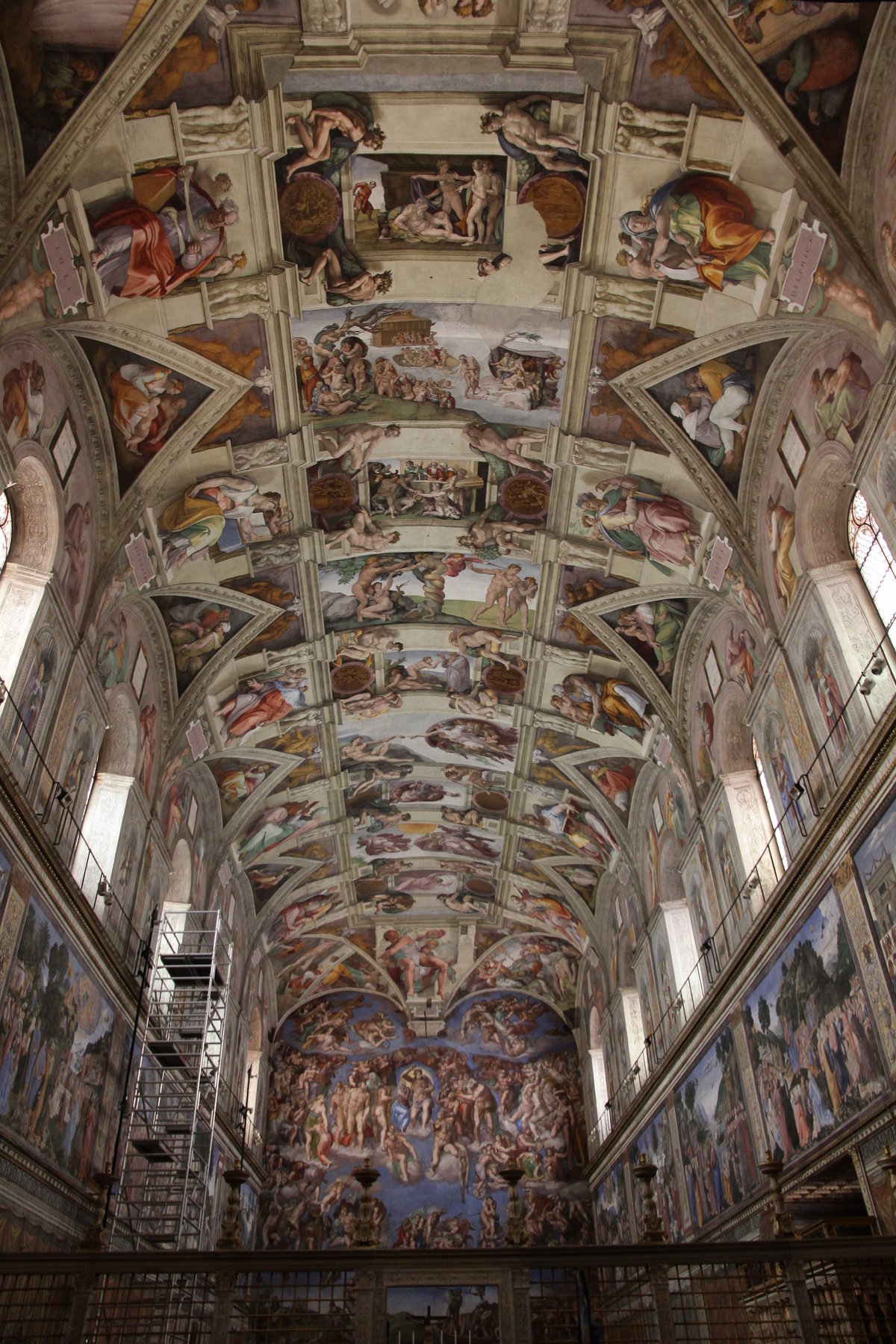 A detail of the Sistine Chapel ceiling showing one bay of Michelangelo's fresco, with a prophet figure seated on a painted architectural throne flanked by ignudi -- naked youths -- in the corners.